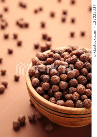 Chocolate corn balls in wooden bowl on brown background. 122023337
