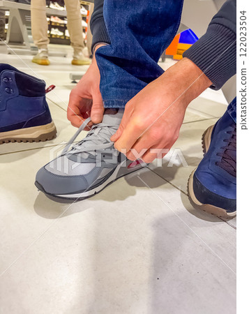 male Trying On grey Sneakers at a Shoe Store. High quality photo 122023504