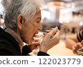 Elderly woman eating out on holiday 122023779
