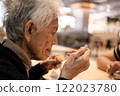 Side view of an elderly woman while holding a spoon who are about to eat 122023780