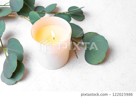 Burning aroma candle and green eucaliptus leaves Burning aroma candle and green eucaliptus leaves 122023986