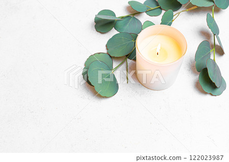 Burning aroma candle and green eucaliptus leaves Burning aroma candle and green eucaliptus leaves 122023987