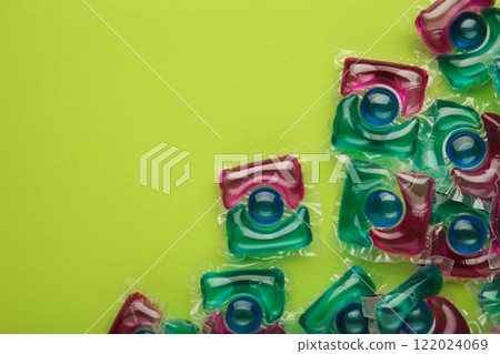 Washing powder in capsules on a green background. Vertical photo. 122024069