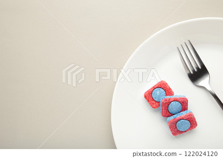 Dishwasher detergent tablet with fork and dishes on grey background. Space for text Dishwasher detergent tablet with fork and dishes on grey background. Space for text 122024120