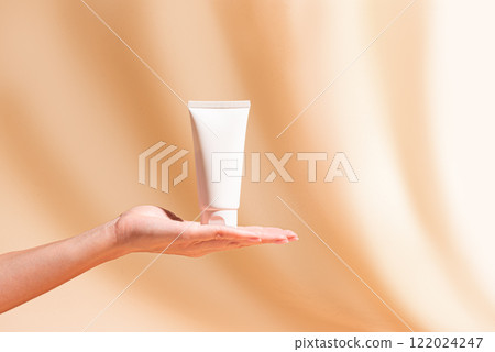 Woman hand hold white cosmetic cream tube 122024247