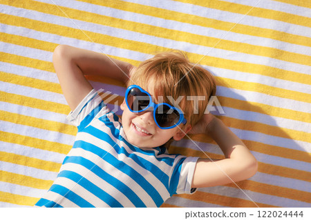 Top view portrait of happy child lying on beach towel on summer vacation 122024444
