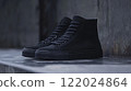 Pair of black shoes with laces on a concrete floor. The shoes are black and have a black sole 122024864