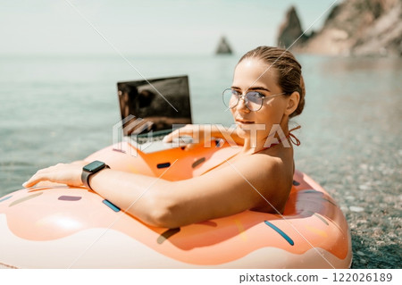 Woman laptop sea. Freelancer woman in sunglases floating on an inflatable big pink donut with a laptop in the sea. People summer vacation rest lifestyle concept Woman laptop sea. Freelancer woman in sunglases floating on an inflatable big pink donut with a laptop in the sea. People summer vacation rest lifestyle concept 122026189