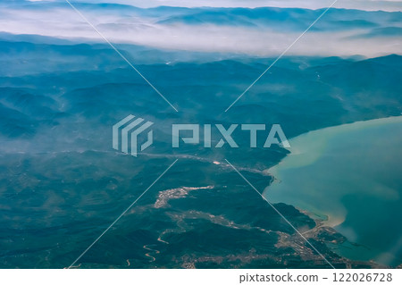 Aerial view from airplane window above green ground. View from the airplane window with beautiful clouds at sunrise. Earth and sky as seen through window of an airplane. High quality photo Aerial view from airplane window above green ground. View from the airplane window with beautiful clouds at sunrise. Earth and sky as seen through window of an airplane. High quality photo 122026728
