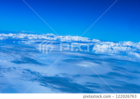 Aerial view from airplane window above green ground. View from the airplane window with beautiful clouds at sunrise. Earth and sky as seen through window of an airplane. High quality photo 122026763