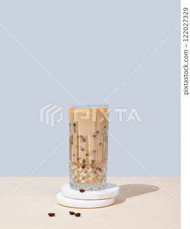 Iced coffee latte in a tall glass with milk on a yellow and blue background 122027329
