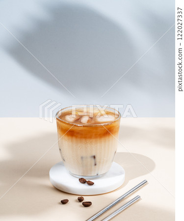 Iced coffee latte in a glass with milk on a yellow and blue background with coffee beans 122027337