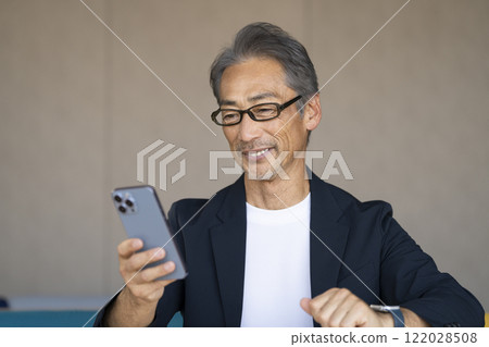 一名 60 多歲的男子戴著眼鏡看著智慧型手機螢幕 122028508