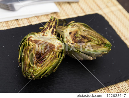 Cooked fried halves artichokes on black stone board Cooked fried halves artichokes on black stone board 122028647
