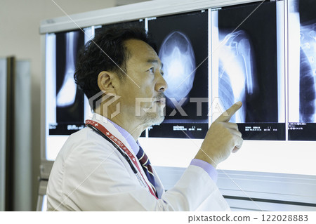 A doctor looking at an X-ray and explaining it. Photo courtesy of Tokyo Electronics College, Denpa Gakuen Corporation. 122028883