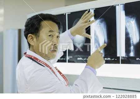 A doctor looking at an X-ray and explaining it. Photo courtesy of Tokyo Electronics College, Denpa Gakuen Corporation. 122028885