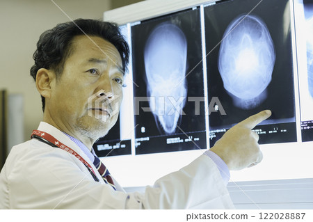 A doctor looking at an X-ray and explaining it. Photo courtesy of Tokyo Electronics College, Denpa Gakuen Corporation. 122028887
