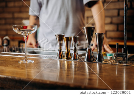 Elegant bar setup with cocktail glass and jiggers, perfect for mixology and bartending concepts Elegant bar setup with cocktail glass and jiggers, perfect for mixology and bartending concepts 122029001