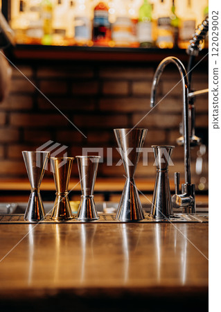 Line of jiggers at a stylish bar counter, symbolizing precision and art in cocktail making Line of jiggers at a stylish bar counter, symbolizing precision and art in cocktail making 122029002