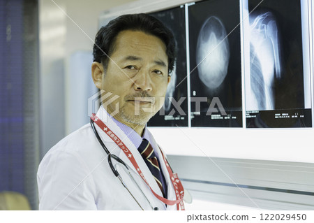 Portrait of a middle-aged doctor in front of an X-ray. Photo courtesy of Tokyo Electronics College, Denpa Gakuen Corporation. 122029450