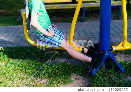 Child using outdoor exercise equipment in a park.  Healthy outdoor activity for kids. 122029455