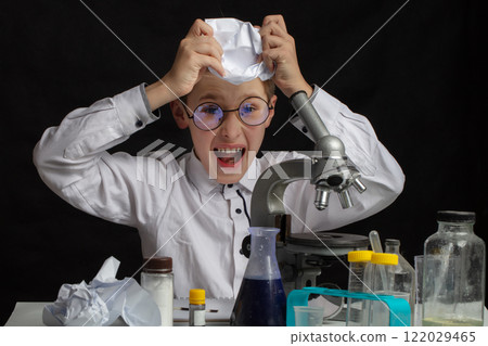 The boy is a scientific researcher with a microscope doing experiments in the laboratory. The boy is a scientific researcher with a microscope doing experiments in the laboratory. 122029465