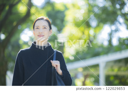 A woman in a coat walking on the sidewalk 122029853
