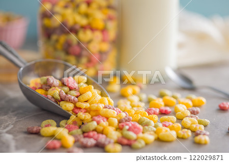 Colorful breakfast cereals in the shape of various fruit on scoop on kitchen table. 122029871
