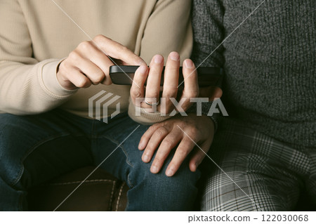 man shows something in his smartphone to his partner man shows something in his smartphone to his partner 122030068