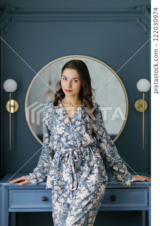 Woman wearing pajamas posing in elegant bedroom with blue walls Woman wearing pajamas posing in elegant bedroom with blue walls 122030974
