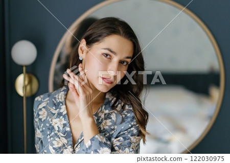 Woman wearing pajamas posing in elegant bedroom with blue walls Woman wearing pajamas posing in elegant bedroom with blue walls 122030975