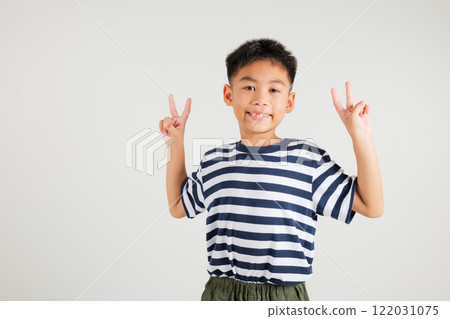 Asian young kid boy showcases optimism and peace by gesturing victory and peace signs in a studio shot with a white background. primary child joyful smile speaks of success, V sign finger Asian young kid boy showcases optimism and peace by gesturing victory and peace signs in a studio shot with a white background. primary child joyful smile speaks of success, V sign finger 122031075
