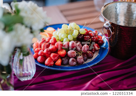 Fresh fruit platter with strawberries, grapes, and peaches on table, perfect for summer events 122031334