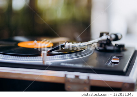 Turntable needle on a spinning vinyl record, evoking vintage charm and timeless music vibes Turntable needle on a spinning vinyl record, evoking vintage charm and timeless music vibes 122031343