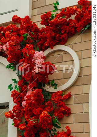decorating the store entrance with red flowers. artificial flowers on exterior wall of the building 122031348