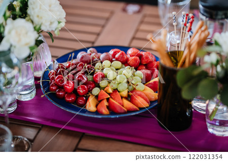 Fresh fruit platter with strawberries, grapes, and peaches on table, perfect for summer events Fresh fruit platter with strawberries, grapes, and peaches on table, perfect for summer events 122031354