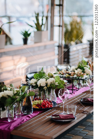 Elegant outdoor table setup with fresh fruit, flowers, and glassware for a festive gathering Elegant outdoor table setup with fresh fruit, flowers, and glassware for a festive gathering 122031360