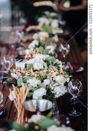 Luxurious dining table setup with flowers, appetizers, and wine glasses for an elegant celebration 122031371