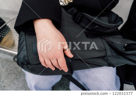 girl's hand lies on backpack. protection from theft of things in a backpack girl's hand lies on backpack. protection from theft of things in a backpack 122031577