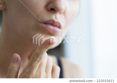 Woman with cream for lips on her finger. Closeup, selective focus. Woman with cream for lips on her finger. Closeup, selective focus. 122031611