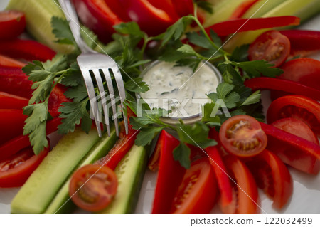 Sliced vegetables with sauce and a fork. Snack dish for a buffet table. 122032499