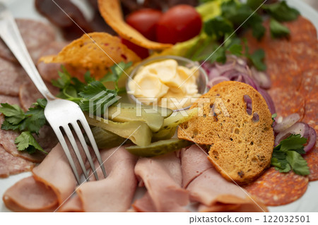 On a plate, an appetizer of sliced meat with croutons and vegetables. 122032501