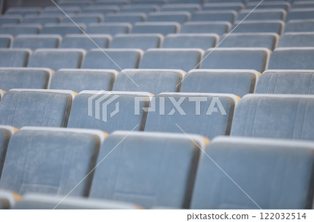 A row of empty blue chairs in the auditorium. 122032514
