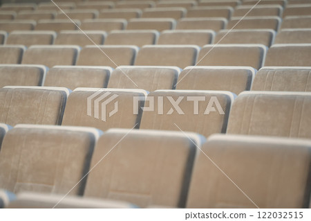 A row of empty beige chairs in the auditorium. 122032515