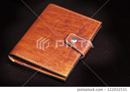 Brown leather wallet with a button fastener on a dark background. Brown leather wallet with a button fastener on a dark background. 122032531