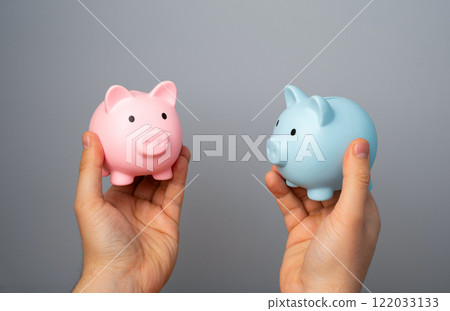 Blue and pink piggy banks in hands. Concept of different budgets of partners or spouses with their needs and incomes. Consumer gender patterns. Separate budget. 122033133