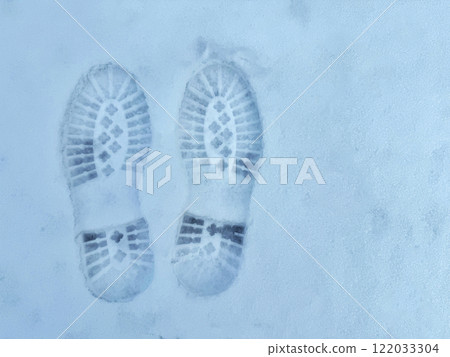 Two boot prints are visible in the snow. Concept of tracks in snow. Two boot prints are visible in the snow. Concept of tracks in snow. 122033304