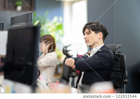 Office work image A man stretching in front of a computer Office work image A man stretching in front of a computer 122033544