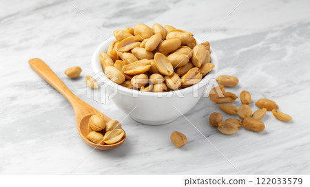 Peanuts in white bowl with wood spoon on marble table background 122033579