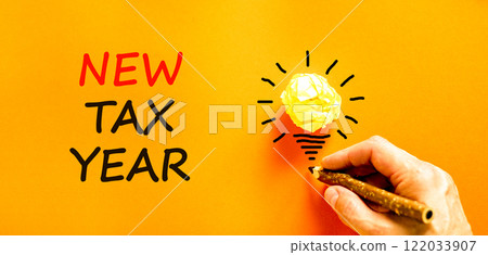 New tax year symbol. Concept words New tax year on beautiful orange paper. Beautiful orange background. Businessman hand. Light bulb icon. Business new tax year concept. Copy space. 122033907